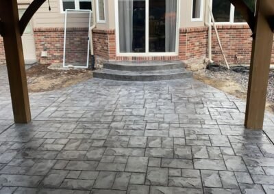 Elegant stamped concrete patio with a cobblestone design by JustFaith Concrete Contractors, enhancing a cozy residential backyard in Portland.