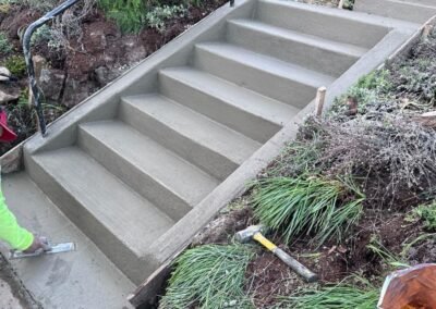 Concrete contractor from JustFaith meticulously finishing a newly constructed concrete staircase in Portland, demonstrating attention to detail and craftsmanship.