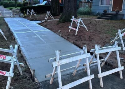 Early morning view of a freshly installed concrete sidewalk by JustFaith Concrete Contractors, cordoned off with signage along a Portland street, showcasing the start of a new day in neighborhood construction.