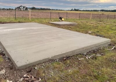 Large, smooth concrete slab by JustFaith Concrete Contractors in a Portland field, ready for outdoor construction or landscaping projects, with rural scenery in the background.